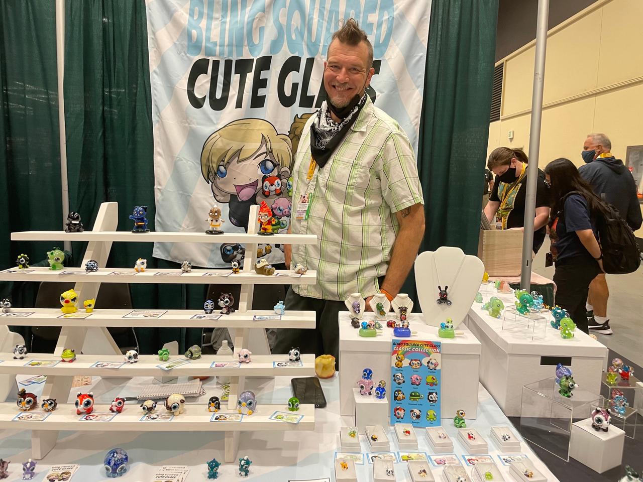 Image of the artist smiling behind his glass figurines.