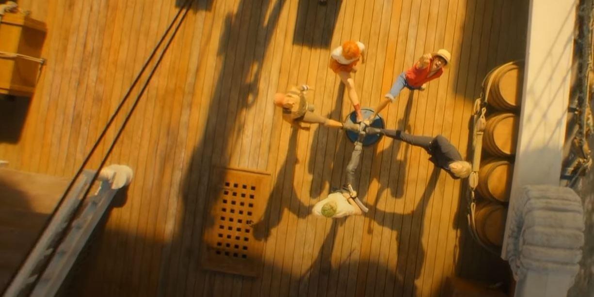 Still image from One Piece, featuring core cast with their foot on a barrel