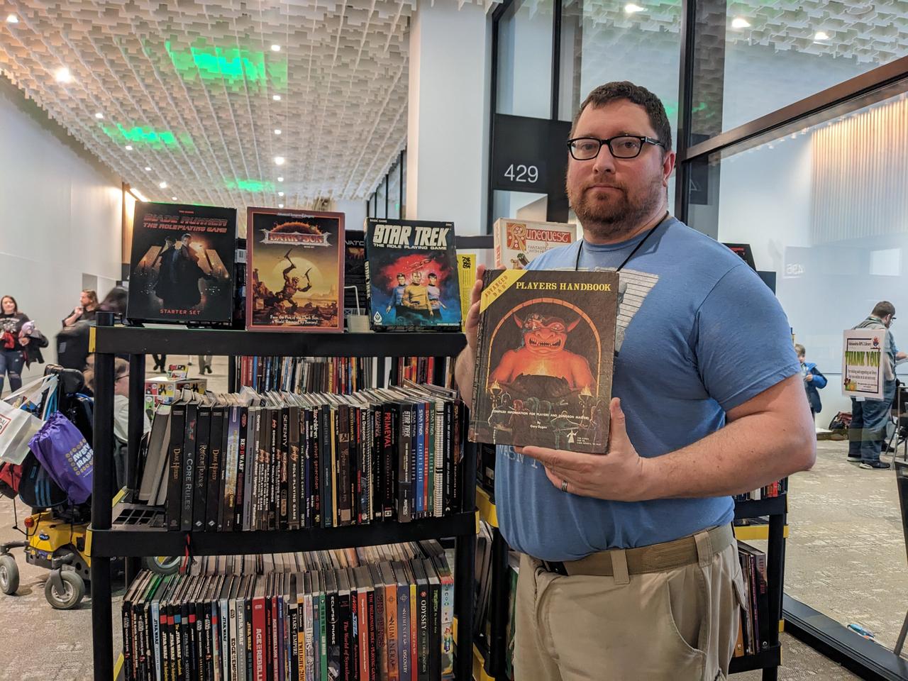 David Carnahan holding a copy of Dungeons and Dragons in front of the library