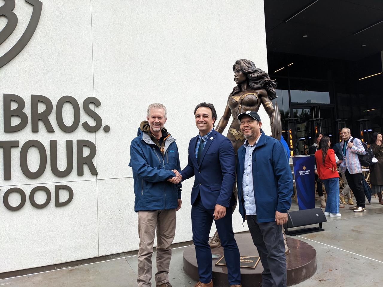 Three men standing in front of Wonder Woman statue