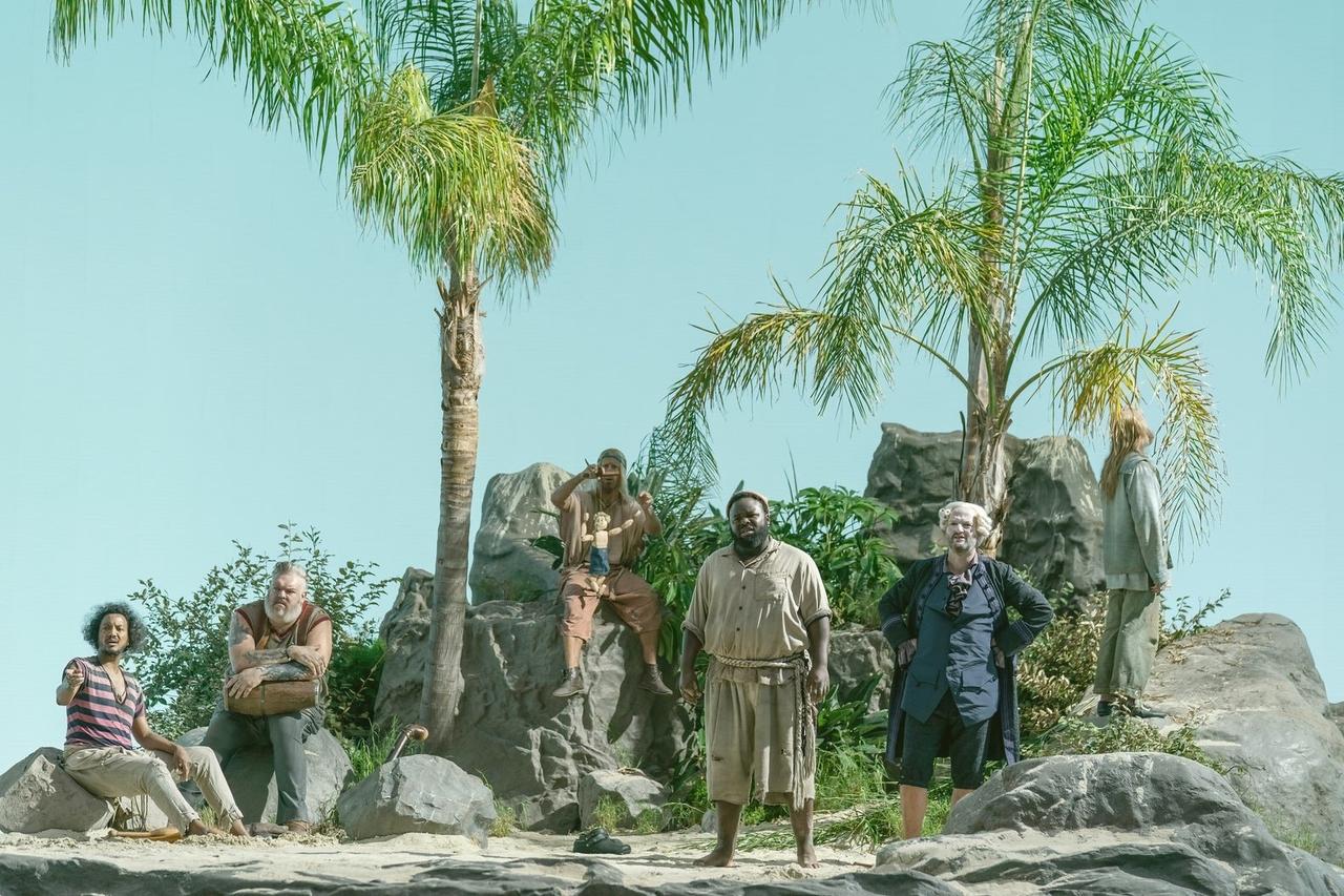 Photograph of Samba Schutte, Kristian Nairn, Nat Faxon, Samson Kayo, Matthew Maher in costume standing on an island in Our Flag Means Death, all looking in the same direction