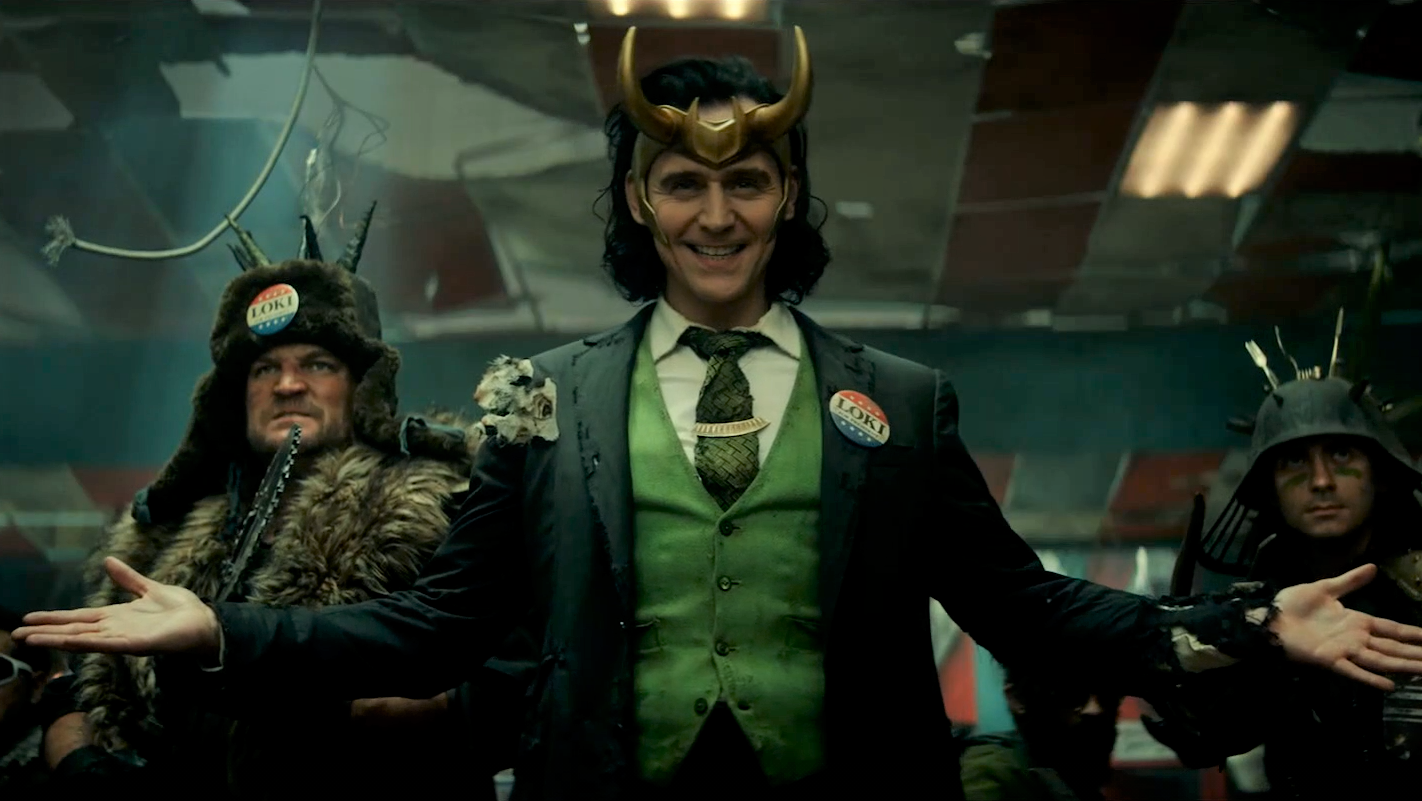 Still image of Loki smiling and wearing a Vote for Loki button