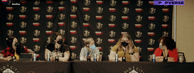 Photograph with Popverse logo featuring the panel sitting in front of a Reedpop Emerald City Comic Con backdrop